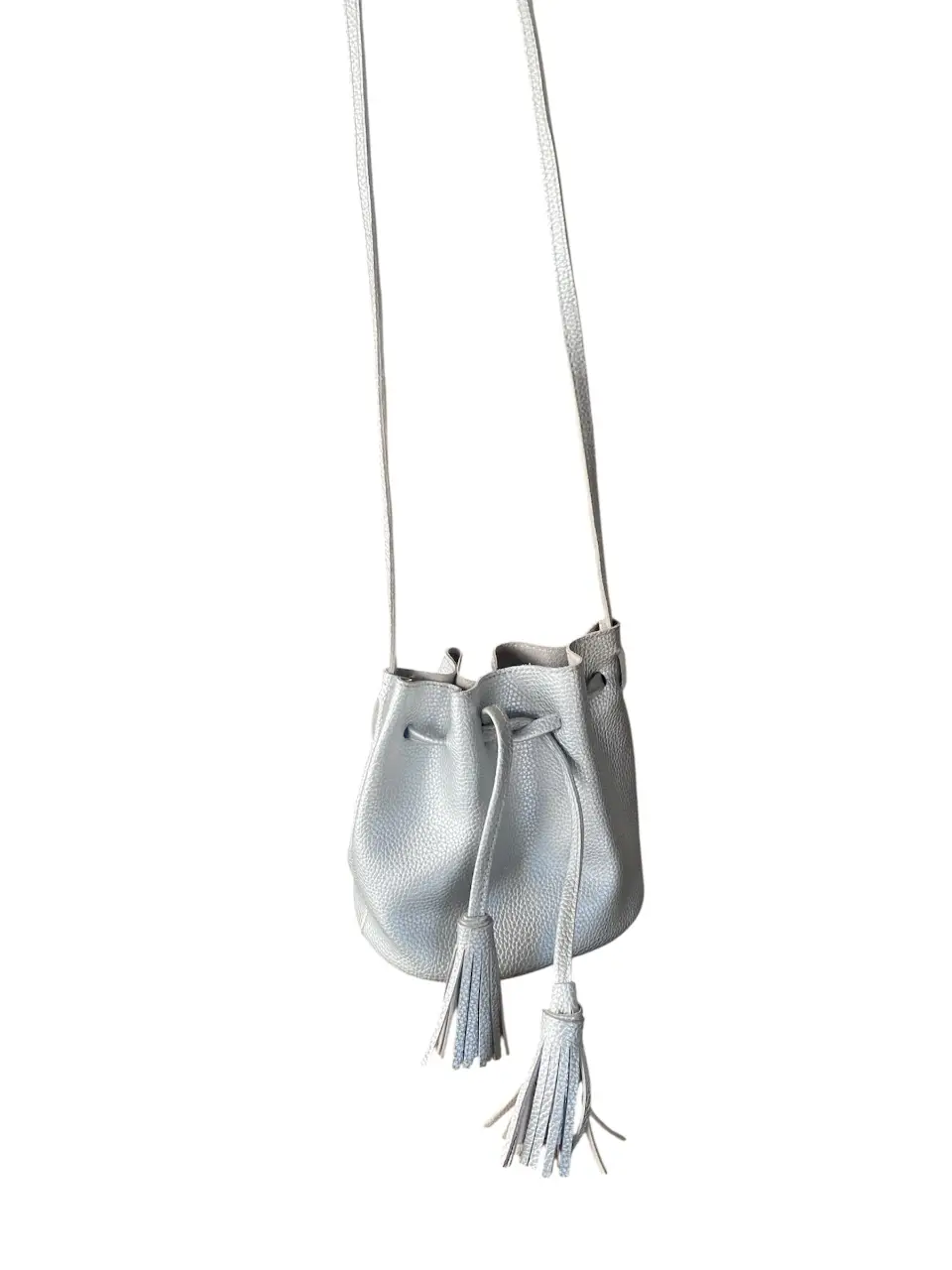 Cartera bandolera tipo saco, de color gris claro. Ideal para un look casual y moderno. Cuenta con dos borlas decorativas. 