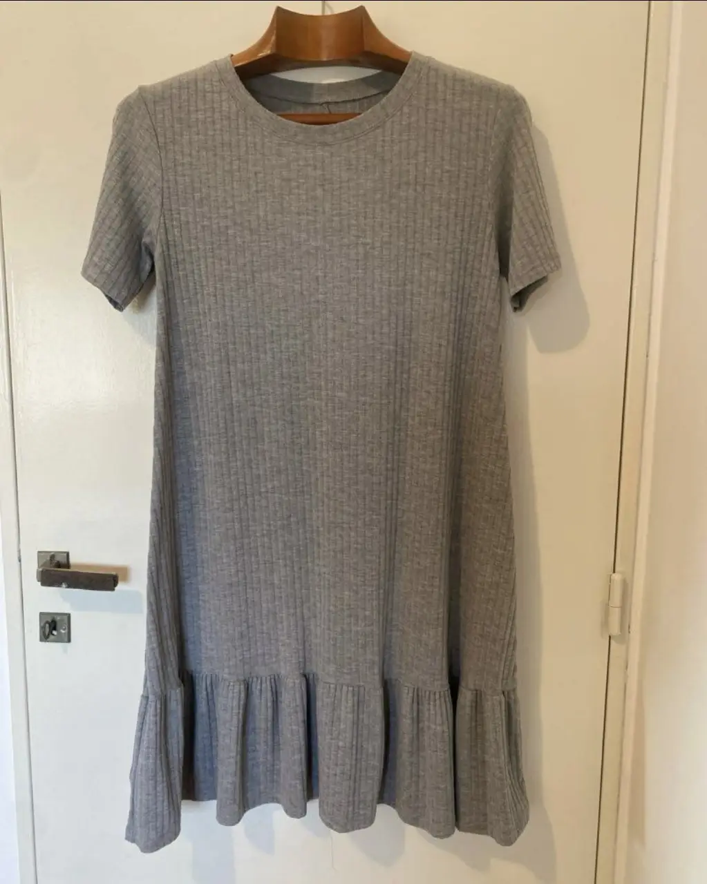 Vestido midi de punto acanalado en color gris. Diseño con mangas cortas y volados en el bajo. Ideal para un look casual y cómodo.