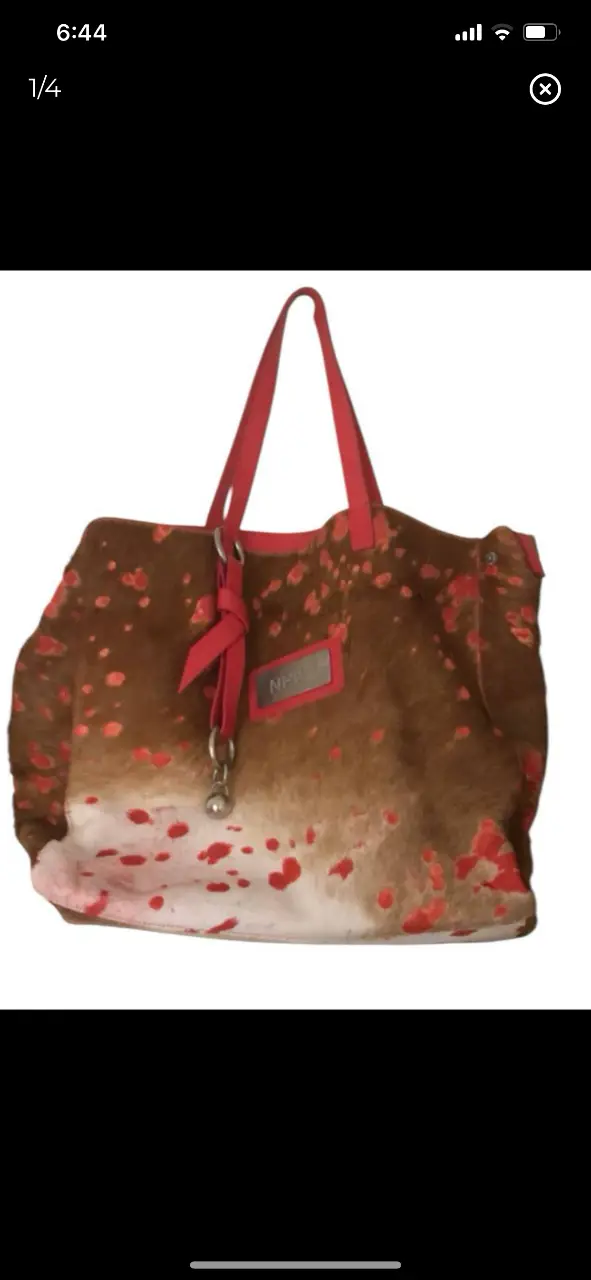 Cartera tote bag de cuero con estampado de manchas rojas y manijas rojas. Con etiqueta de la marca NHUR.