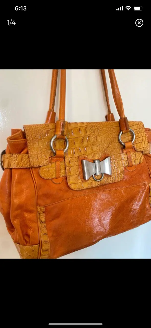 Cartera de cuero naranja con detalles en cuero simil cocodrilo. Posee manijas cortas y una correa larga para llevar al hombro. Interior espacioso con bolsillos. 26x36cm