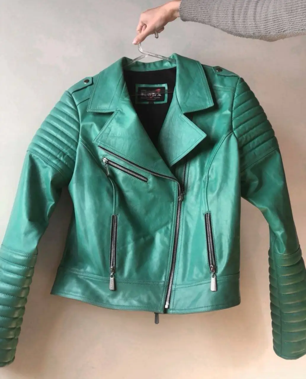 Campera de cuero verde estilo biker para mujer. Confeccionada en cuero de alta calidad, esta campera presenta un diseño clásico con detalles de cremalleras y costuras en los hombros y mangas. Ideal para un look rockero y moderno. axilas 53, hombros 40