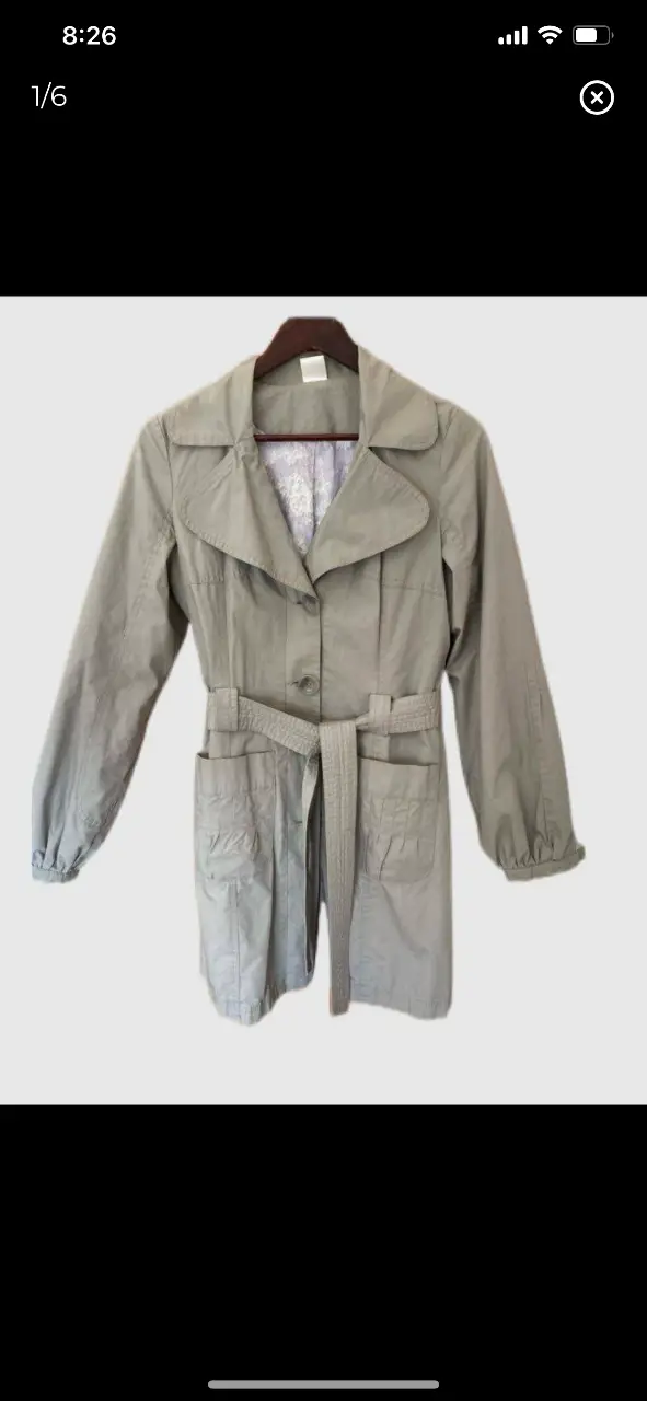 Trench coat gris con cinturón, bolsillos y mangas con detalle. Ideal para un look elegante y versátil.hombros 37 axilas 49 cintura 42 mangas 63 largo 88 