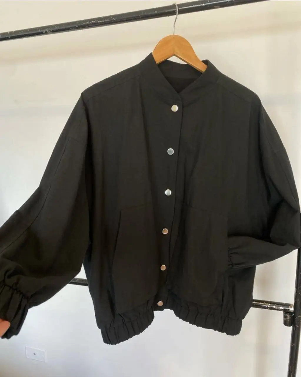 Campera bomber negra de tela liviana, con botones plateados y detalles de puños y cintura elastizados. Ideal para un look casual y moderno.