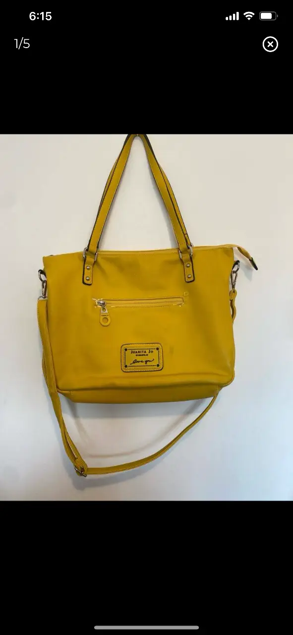 Cartera Juanita Jo amarilla, con correa larga y detalles dorados. Tiene un bolsillo con cierre en la parte trasera y otro interno. Ideal para llevar tus cosas con estilo. tiene saltado el eco cuero en algunas partes. 30x40cm