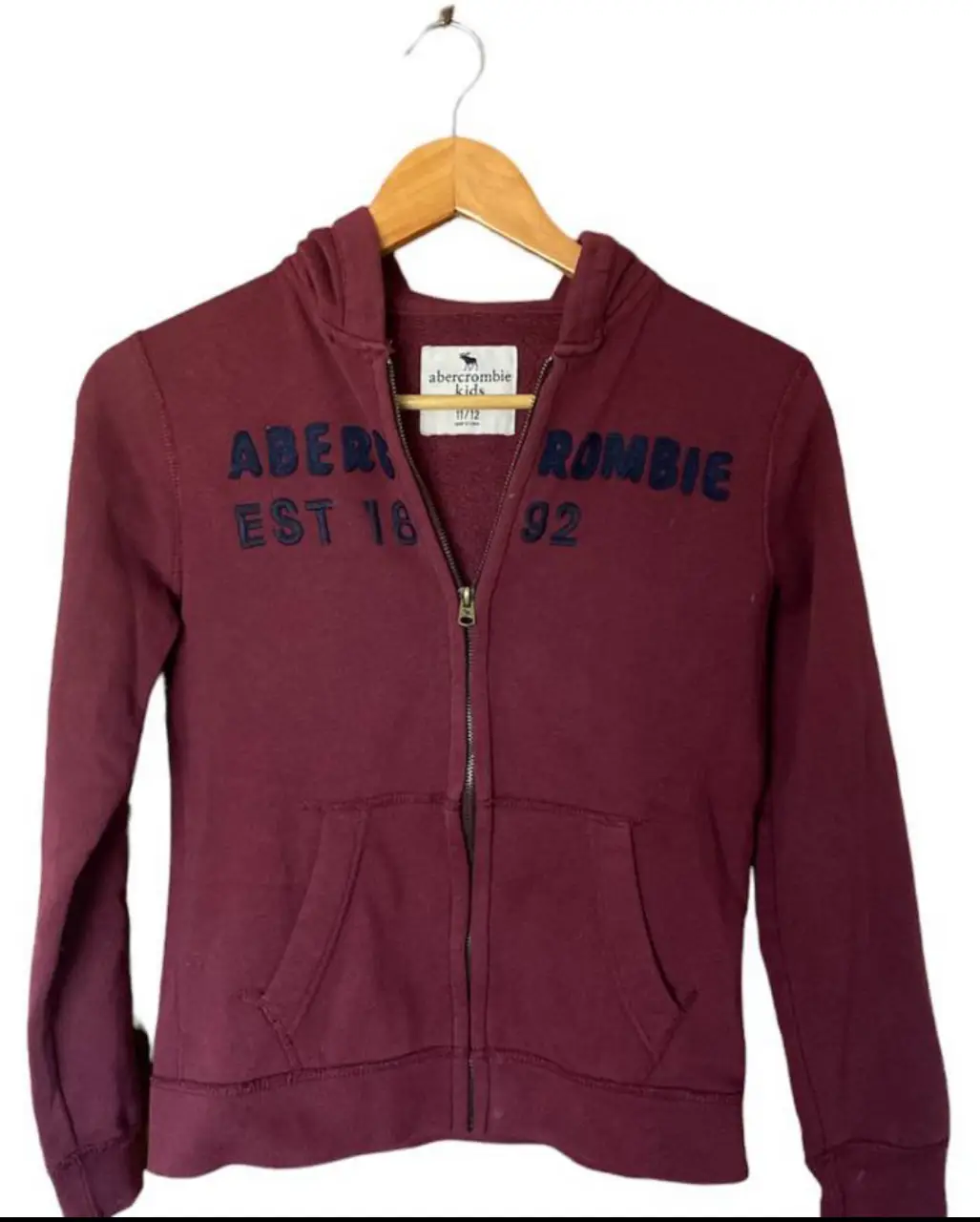 Buzo con cierre Abercrombie Kids, color borgoña, con capucha y bolsillos. Talle 11/12. Ideal para un look casual y abrigado. color bordó largo 55cm. tiene unas manchitas como se ve en las fotos 