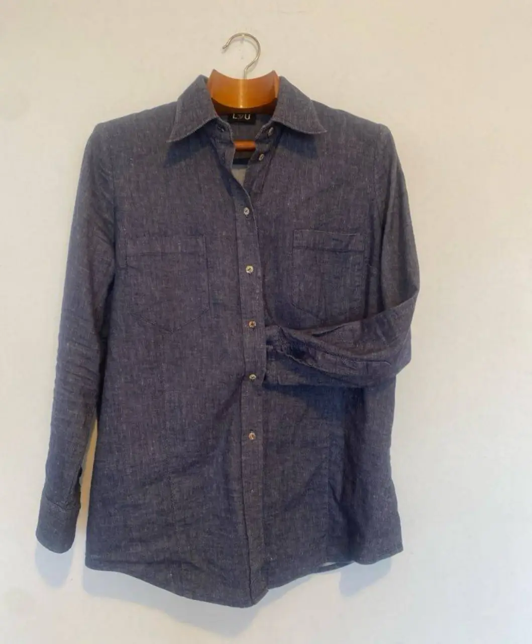 Camisa de lino azul, con dos bolsillos delanteros y botones. Ideal para un look casual y fresco.