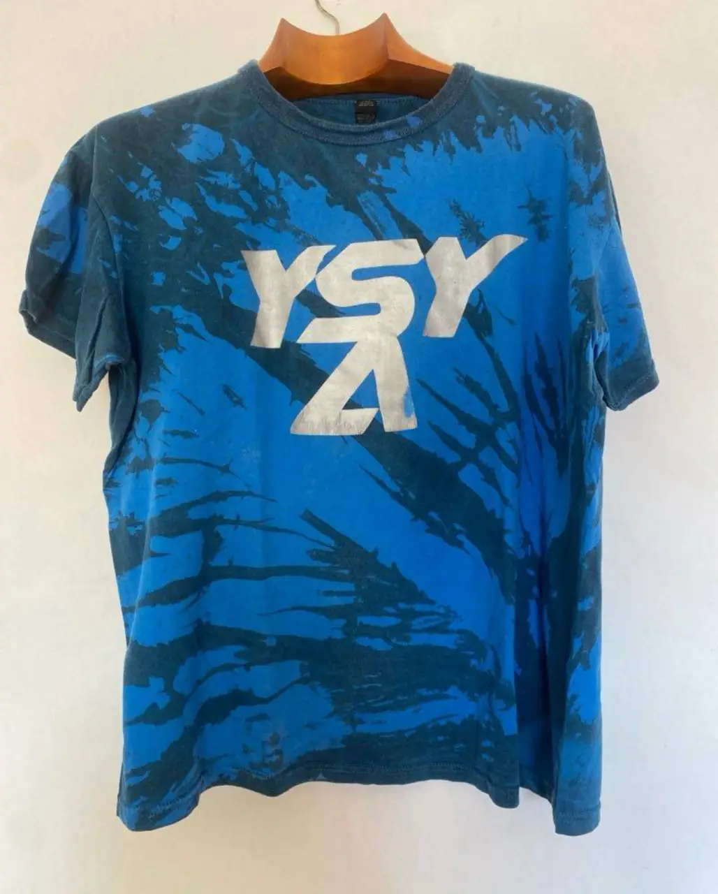 Remera con diseño tie-dye en tonos azules y estampado plateado "YSY" en el frente. En la espalda, lista de fechas y lugares de la gira. Ideal para un look urbano y canchero. hombros 59, axilas 45, largo 63 (según etiqueta es xxl)
