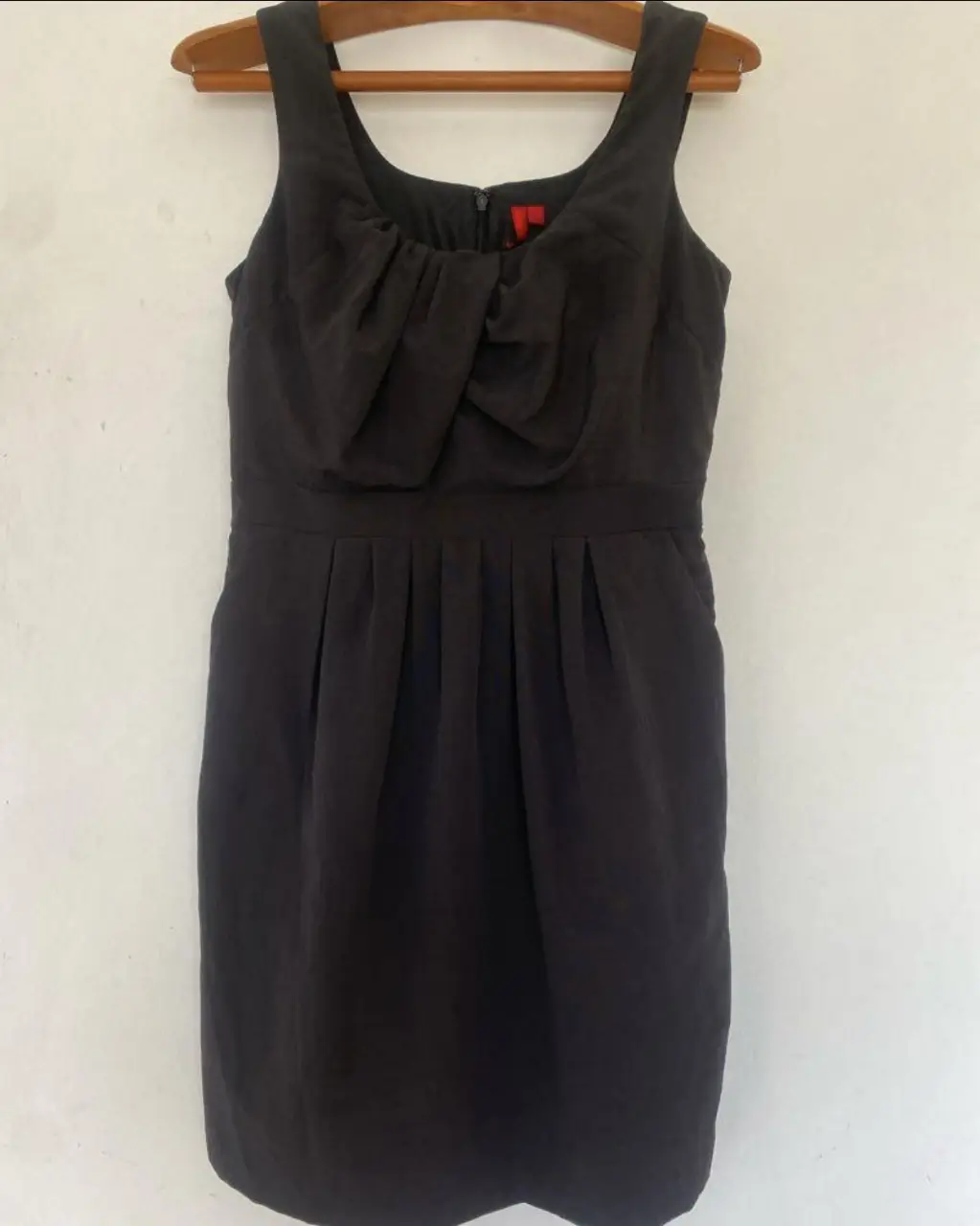 Vestido midi negro con detalle drapeado en el busto y cintura entallada. Diseño elegante con bolsillos laterales y cierre trasero. Ideal para eventos formales o salidas.