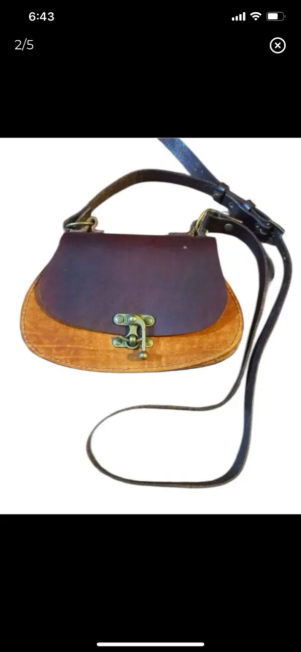 Cartera bandolera artesanal de cuero, con diseño semicircular y cierre metálico. Ideal para un look bohemio y casual. 15x22cm