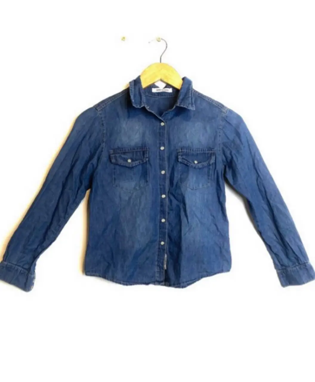 Camisa de jean azul, con dos bolsillos delanteros. Talle 32. Ideal para un look casual y moderno.