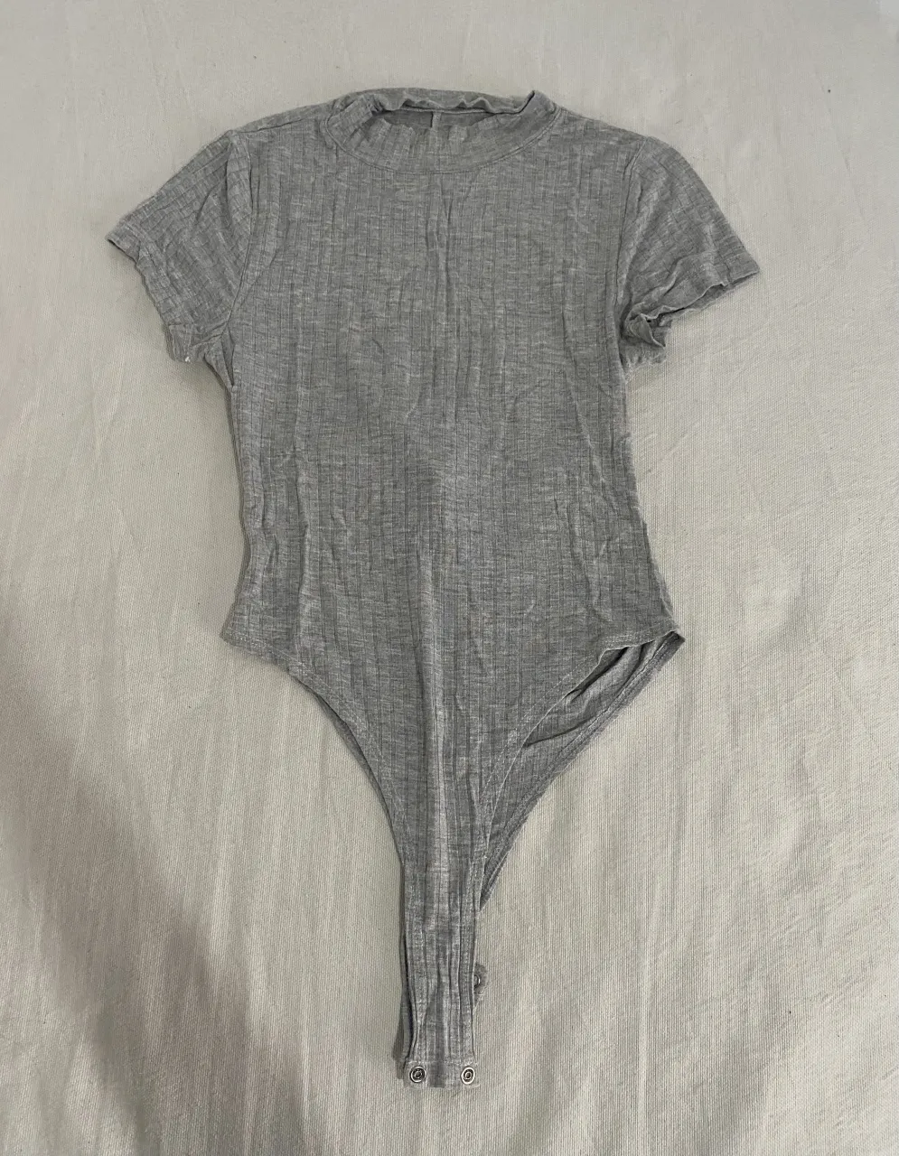 Body de modal gris con cuello alto y mangas cortas. Espalda súper sexy con recorte y tiras para atar. Ideal para un look canchero y moderno.