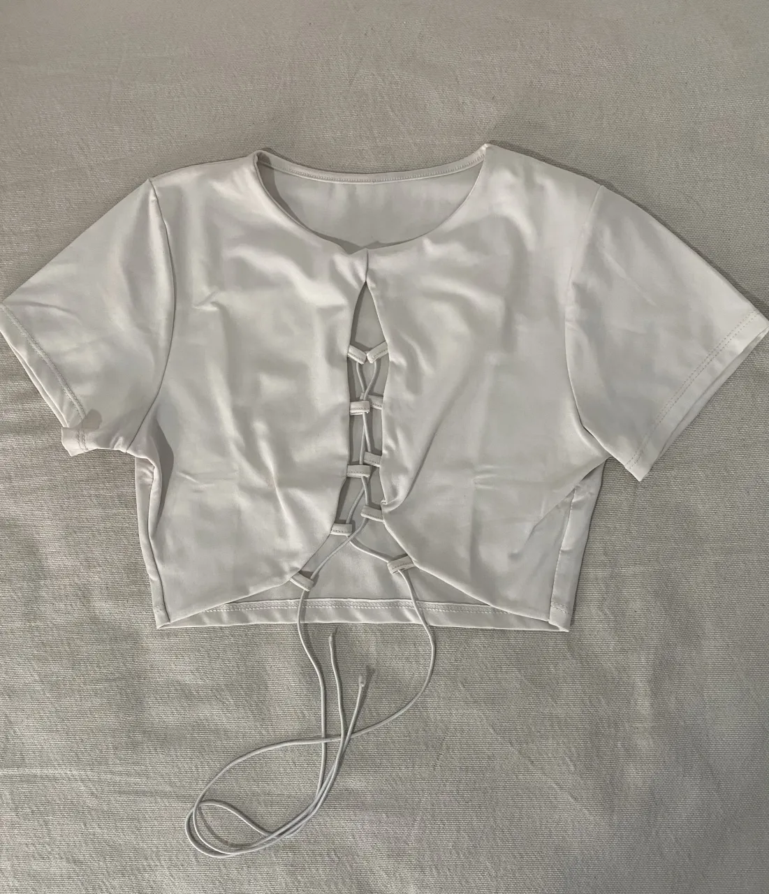 Top blanco súper canchero con escote cruzado y cordones. Ideal para un look de verano o para salir con amigas. ¡No te lo pierdas!