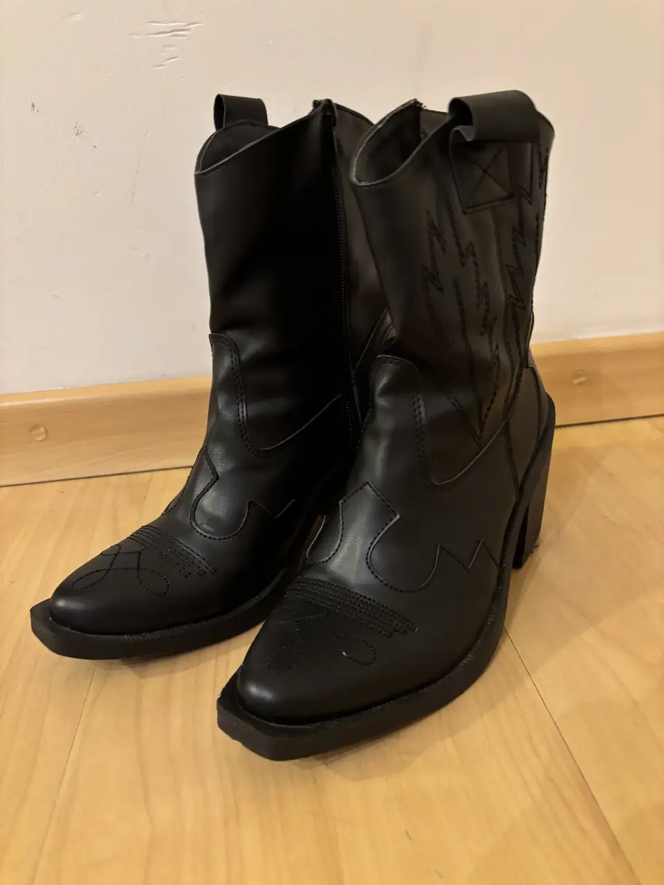 Botas de caña alta negras, estilo cowboy, con detalles de diseño en la parte superior. Ideales para un look moderno y audaz.