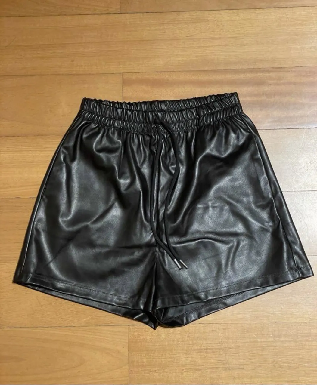 Shorts de cuero sintético negro, tiro alto, con cintura elastizada y cordón ajustable. Ideales para un look canchero y moderno.