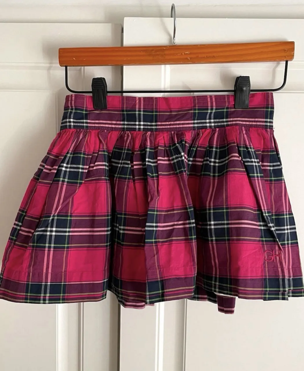 Pollera a cuadros escoceses en tonos fucsia, azul marino y blanco. Diseño con cintura elastizada y fruncido, ideal para un look canchero y cómodo.