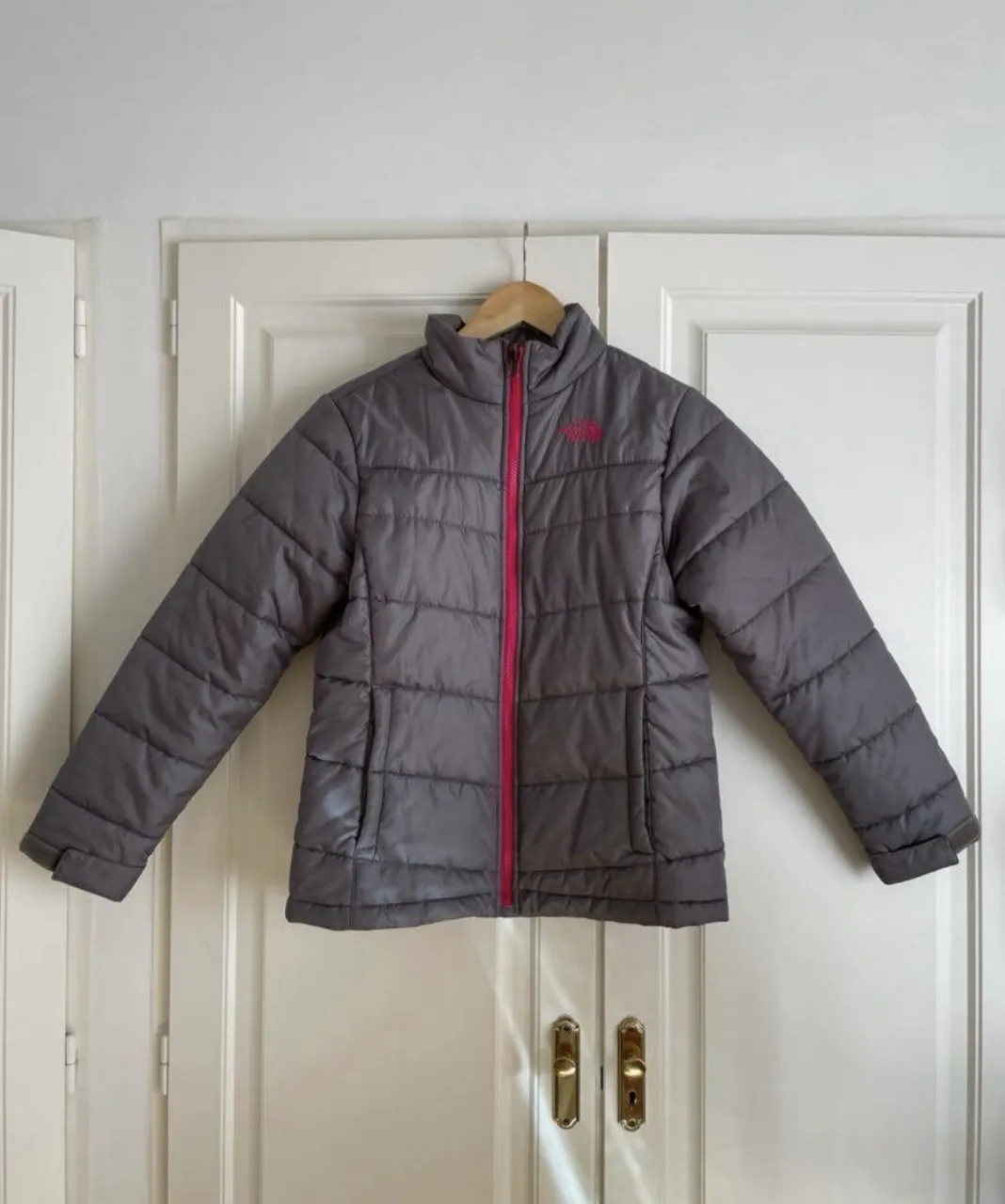 Campera acolchada gris con cierre fucsia. Ideal para mantenerte abrigada en los días fríos.