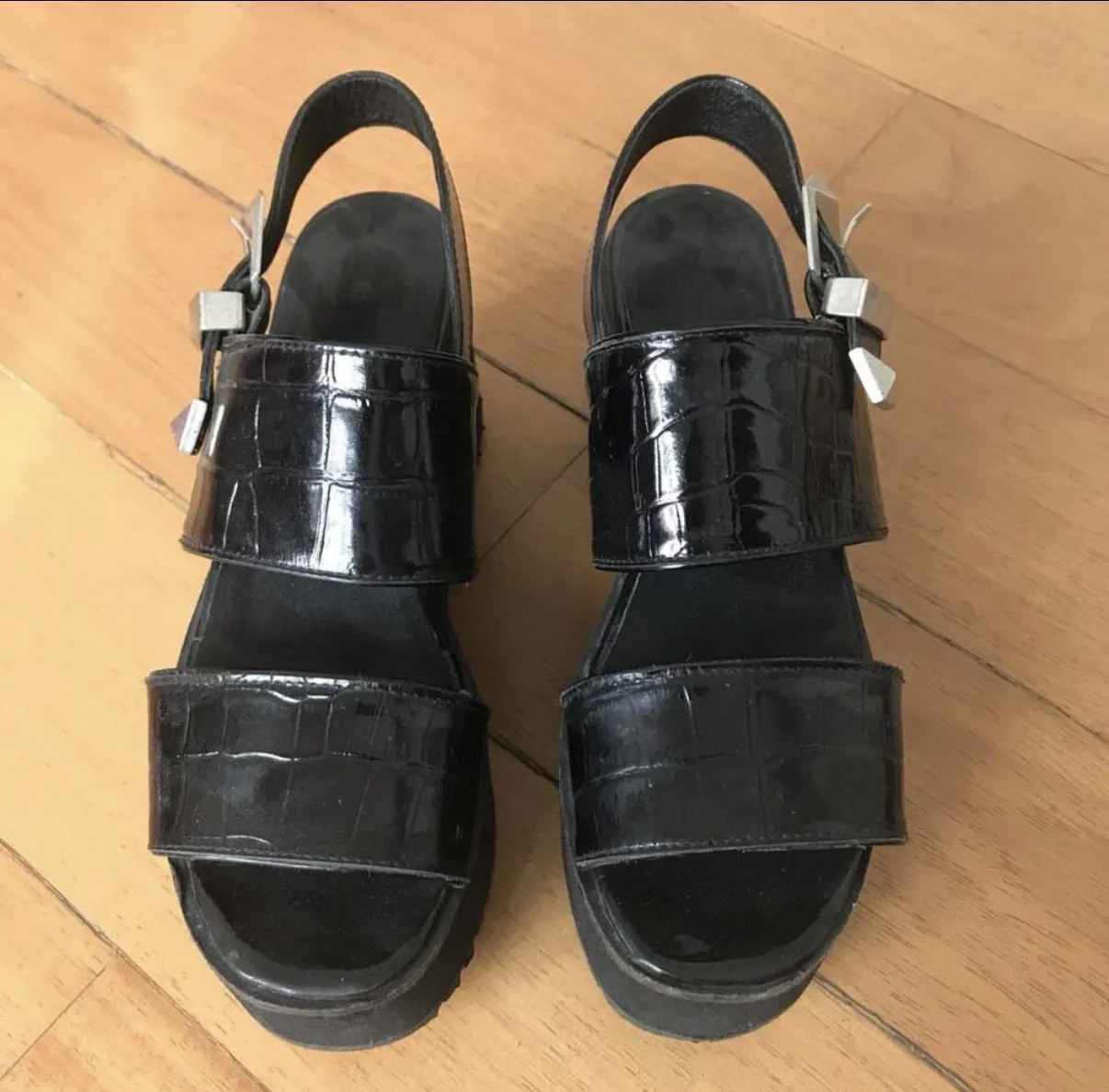 Sandalias negras de plataforma con hebilla y textura de cocodrilo. ¡Perfectas para darle un toque audaz a tu look!