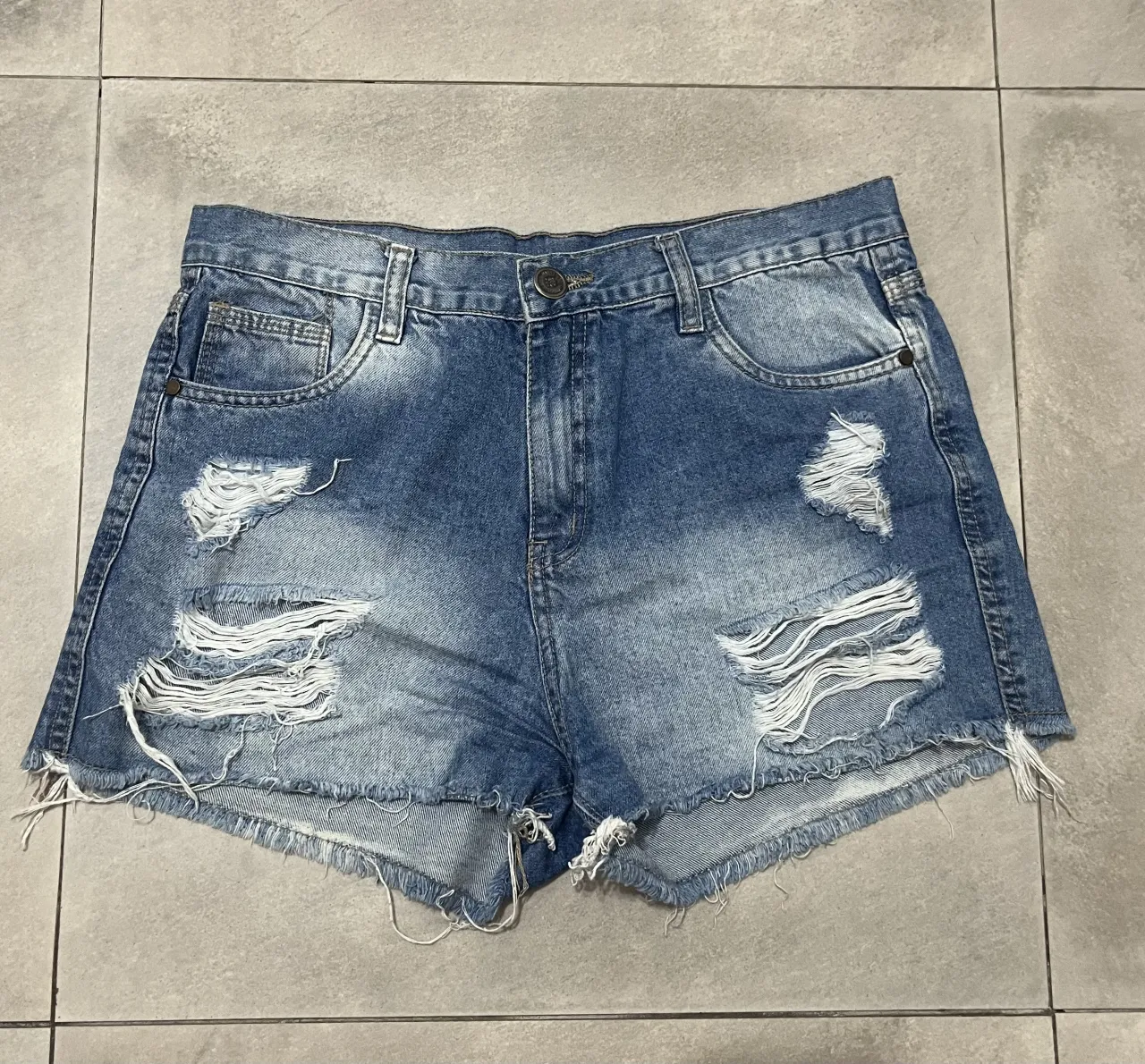 Short de jean con roturas y detalles deshilachados en los bordes.