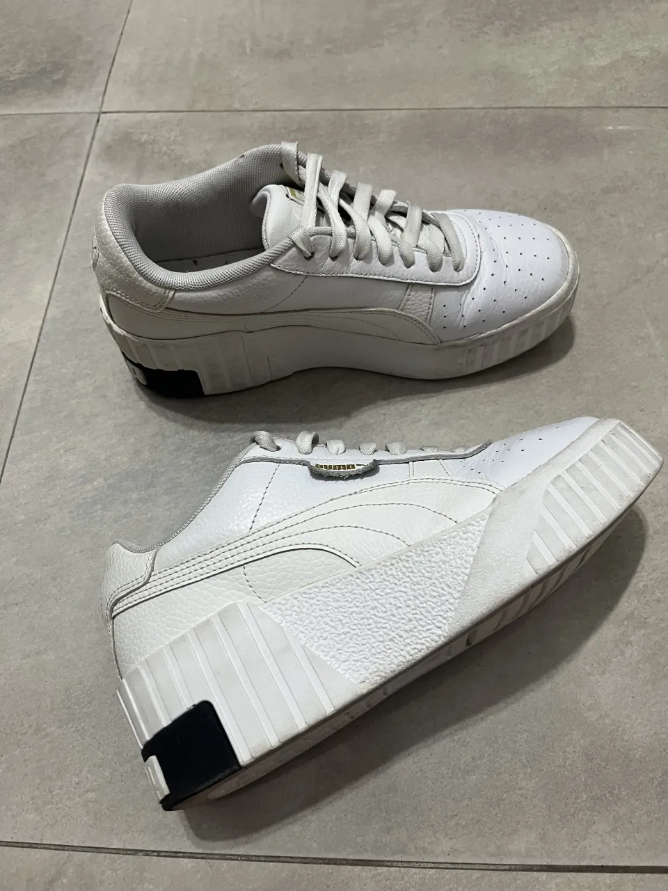 Zapatillas Puma blancas de cuero con detalles en negro en la suela y logo de la marca en los laterales y talón.