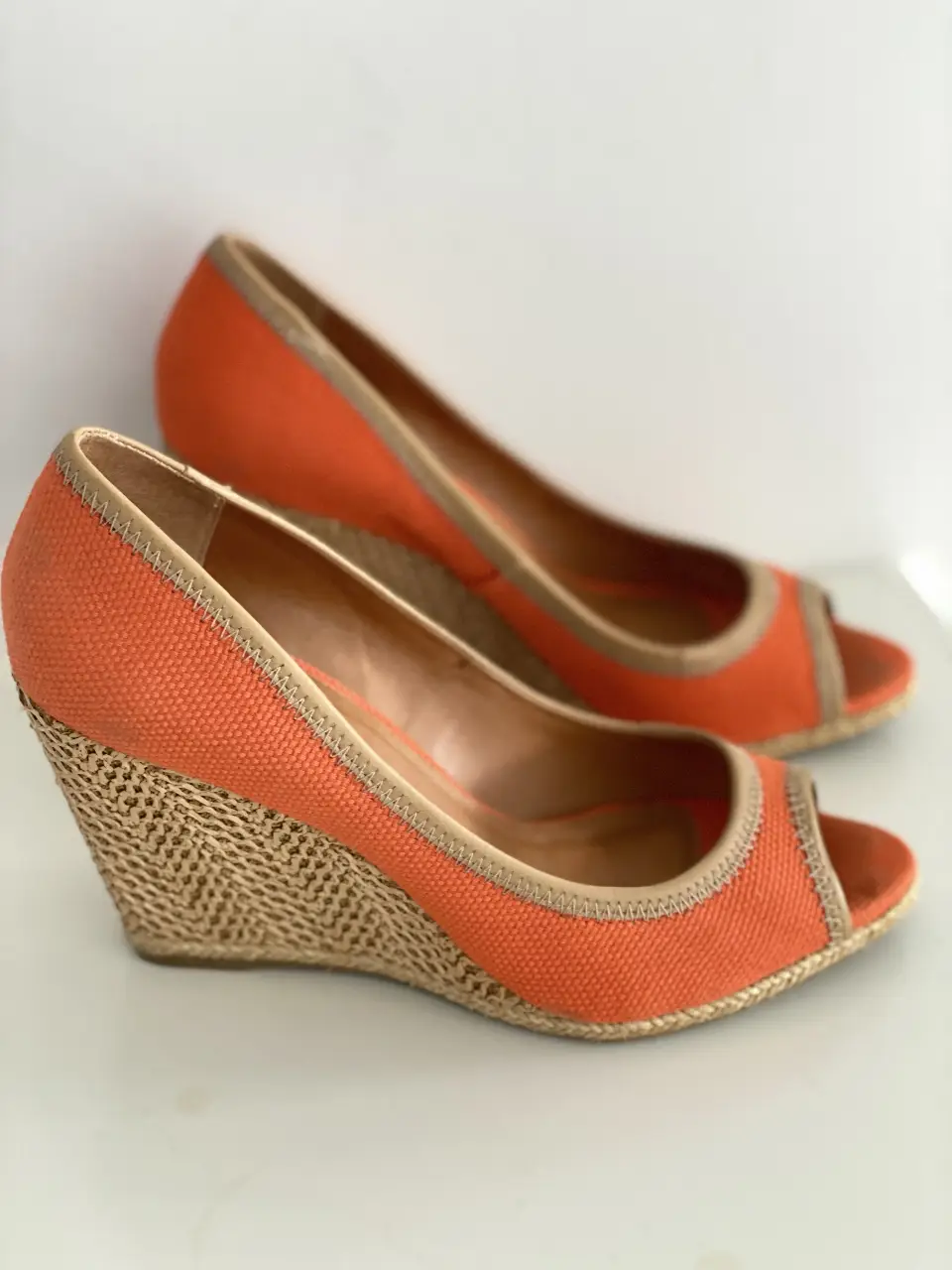 Sandalias de cuña naranja con detalles en beige. Ideales para un look de verano.