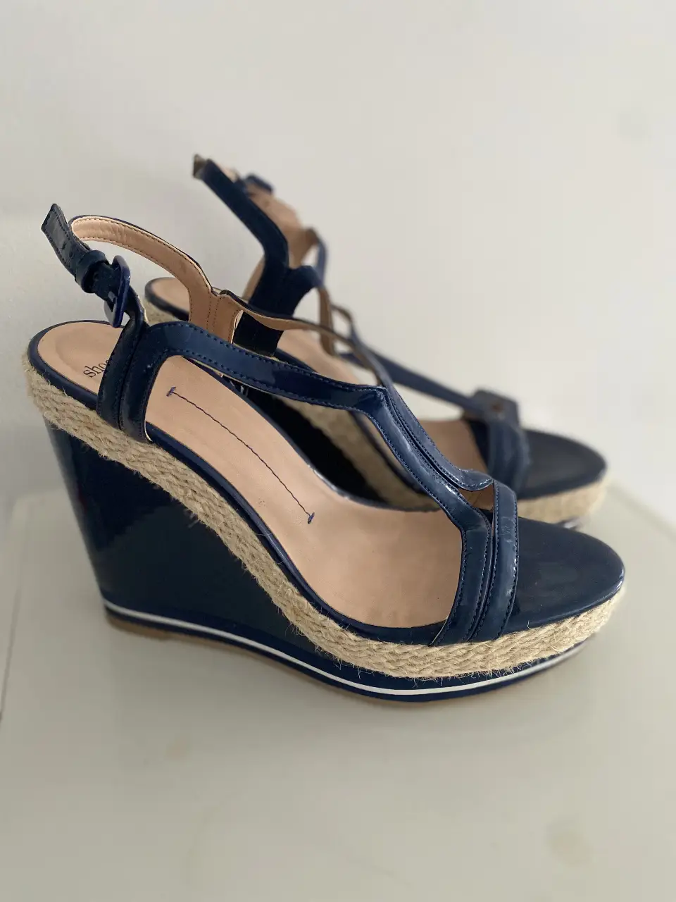 Sandalias de cuña Shoestock azul marino con detalles en beige y suela de yute. Tiras en la parte superior y hebilla ajustable en el tobillo. Ideales para un look de verano elegante y cómodo.