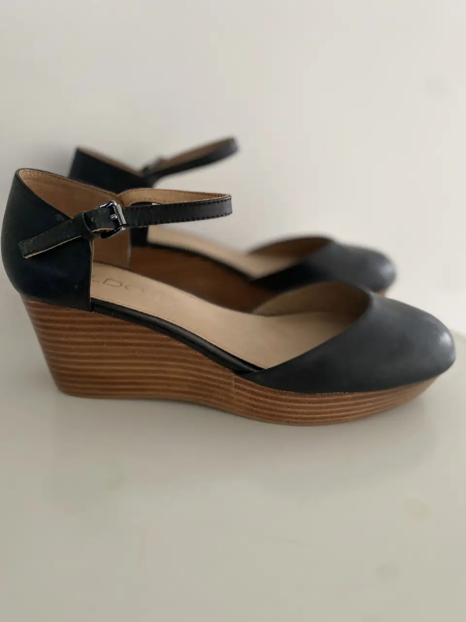Sandalias de cuña negras de cuero sintético con pulsera en el tobillo. Ideales para un look elegante y cómodo.