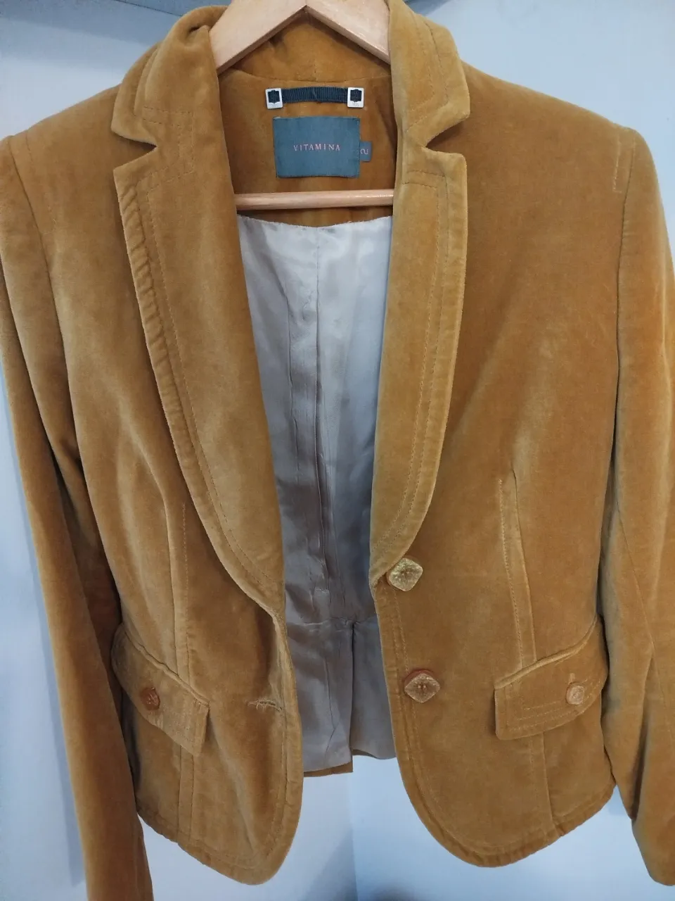 Elegante blazer de terciopelo color mostaza, con botones decorativos y bolsillos. Ideal para un look sofisticado y con estilo.