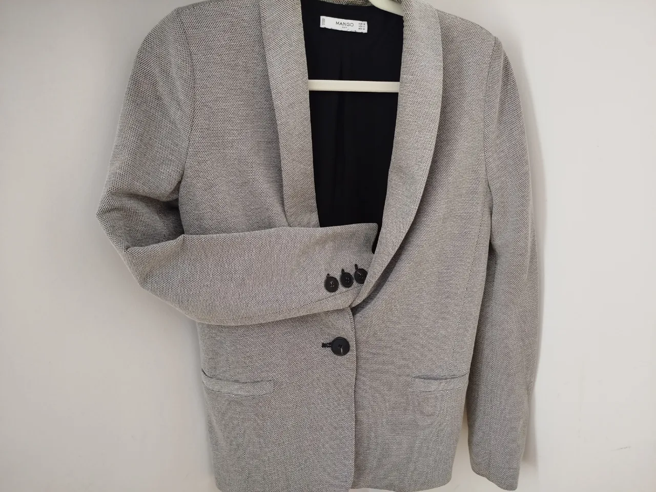 Blazer de mujer Mango, gris con textura, con botones y bolsillos. Ideal para un look elegante y moderno.