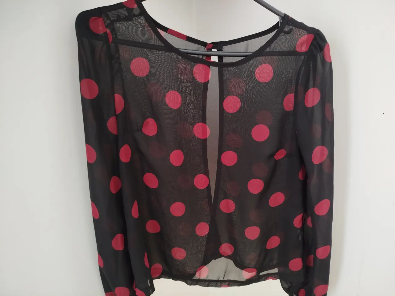 Blusa de mujer de gasa negra con lunares rojos. Manga larga con puño y botón. Ideal para un look elegante y moderno.
