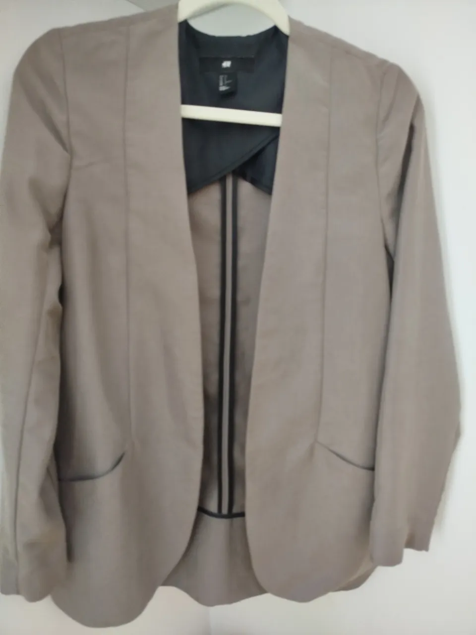 Blazer de mujer color gris claro, de la marca H&M. Talle US 6, con solapas y bolsillos delanteros. Ideal para un look elegante y versátil.
