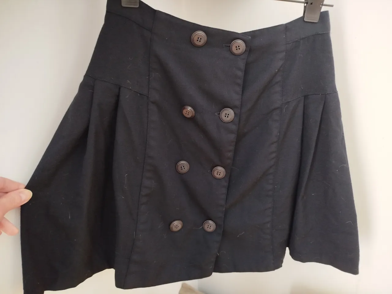 Pollera negra con botones, ideal para un look elegante y sofisticado. Perfecta para combinar con blusas o camisas.
