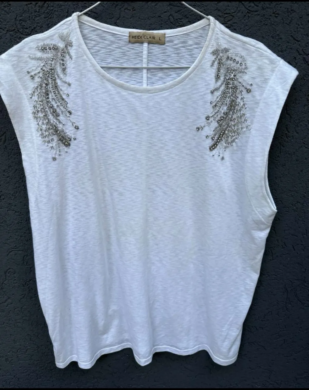 Musculosa blanca con detalles bordados en los hombros. Perfecta para un look canchero y con un toque de brillo.