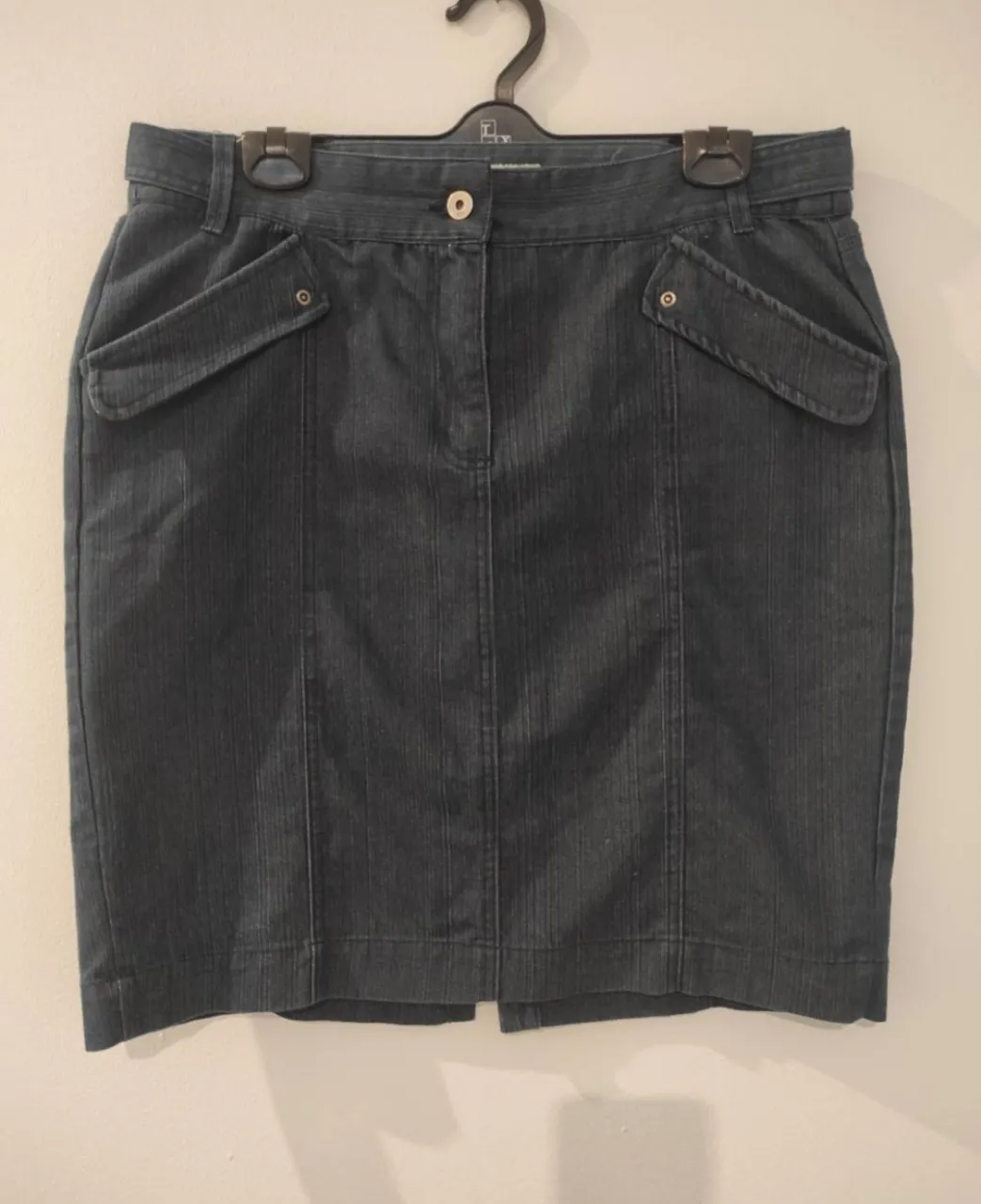 Pollera de jean azul oscuro, tiro alto, con bolsillos frontales y traseros. Diseño clásico y versátil, ideal para combinar con diversas prendas.