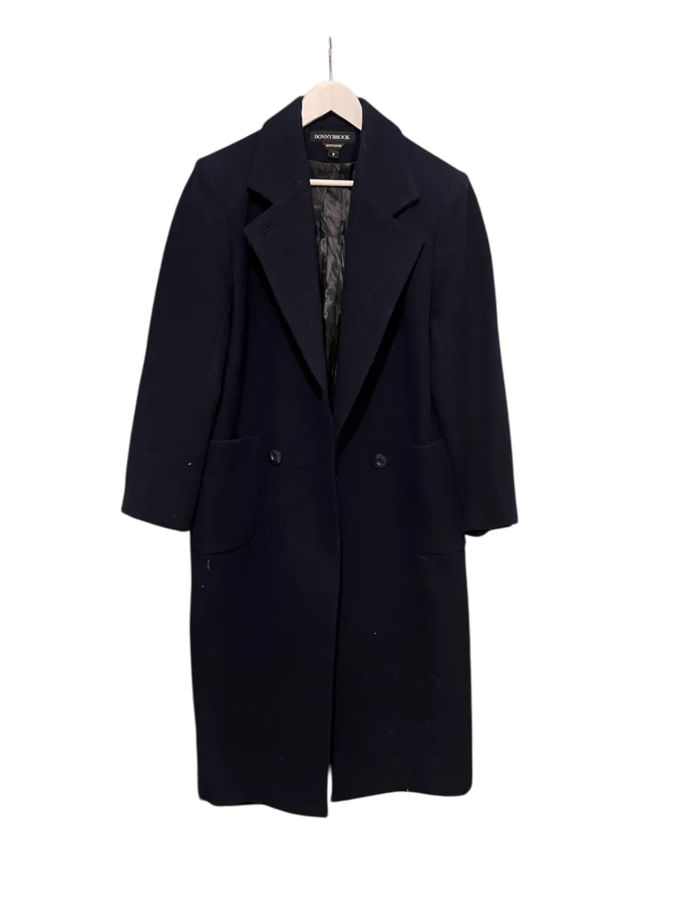 Abrigo largo de paño, color azul marino, con solapa ancha y dos botones al frente. Posee bolsillos laterales.