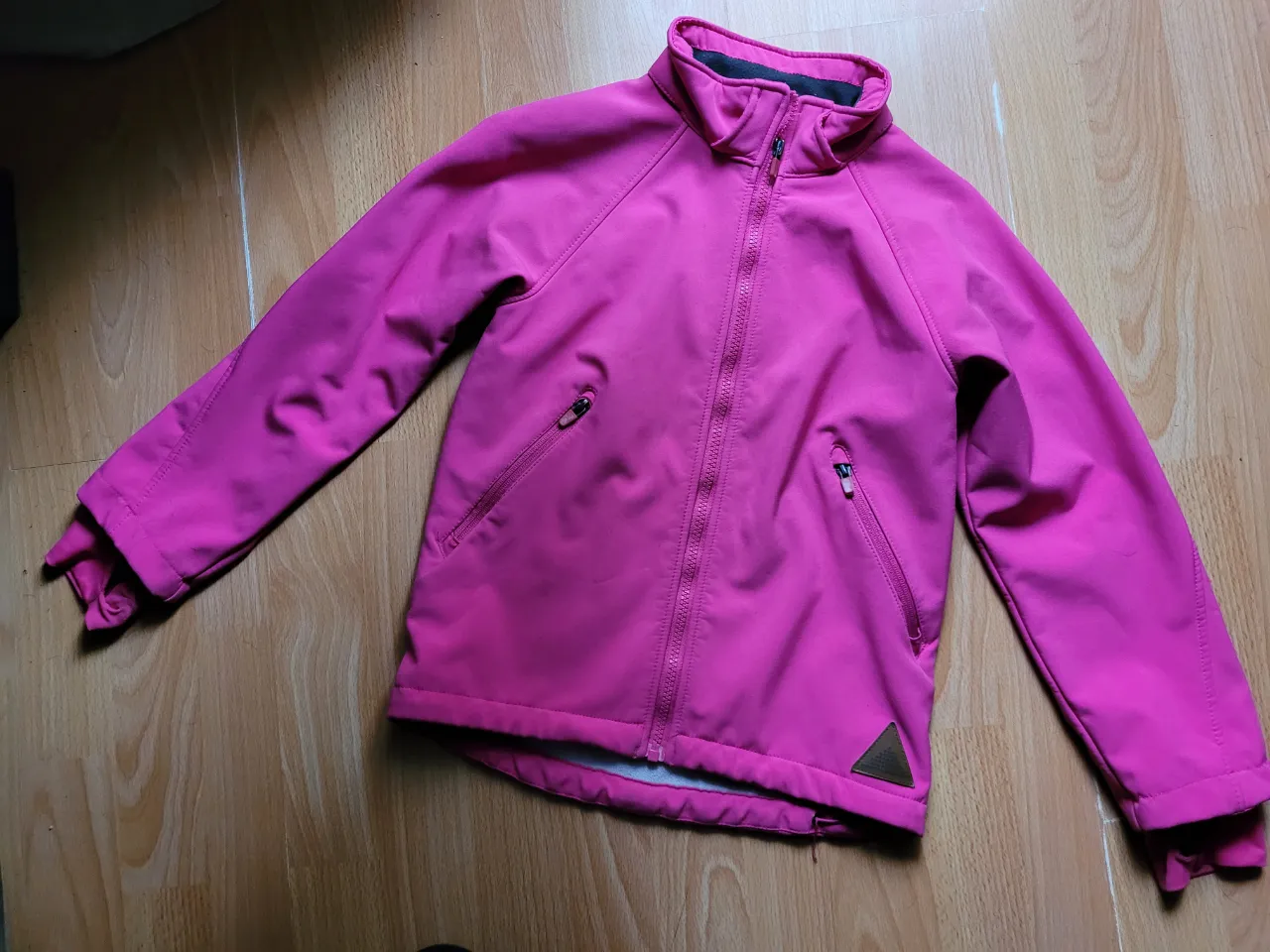Campera deportiva fucsia para niña, con cierre y bolsillos. Ideal para actividades al aire libre.
