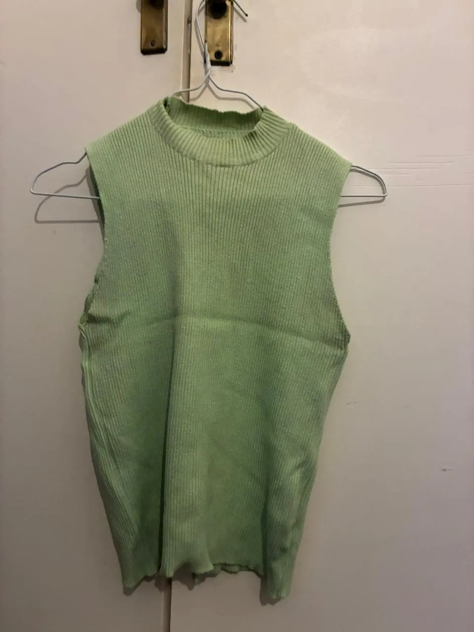 Musculosa de tejido de punto en color verde claro, con cuello alto y corte recto. Ideal para un look casual y fresco.