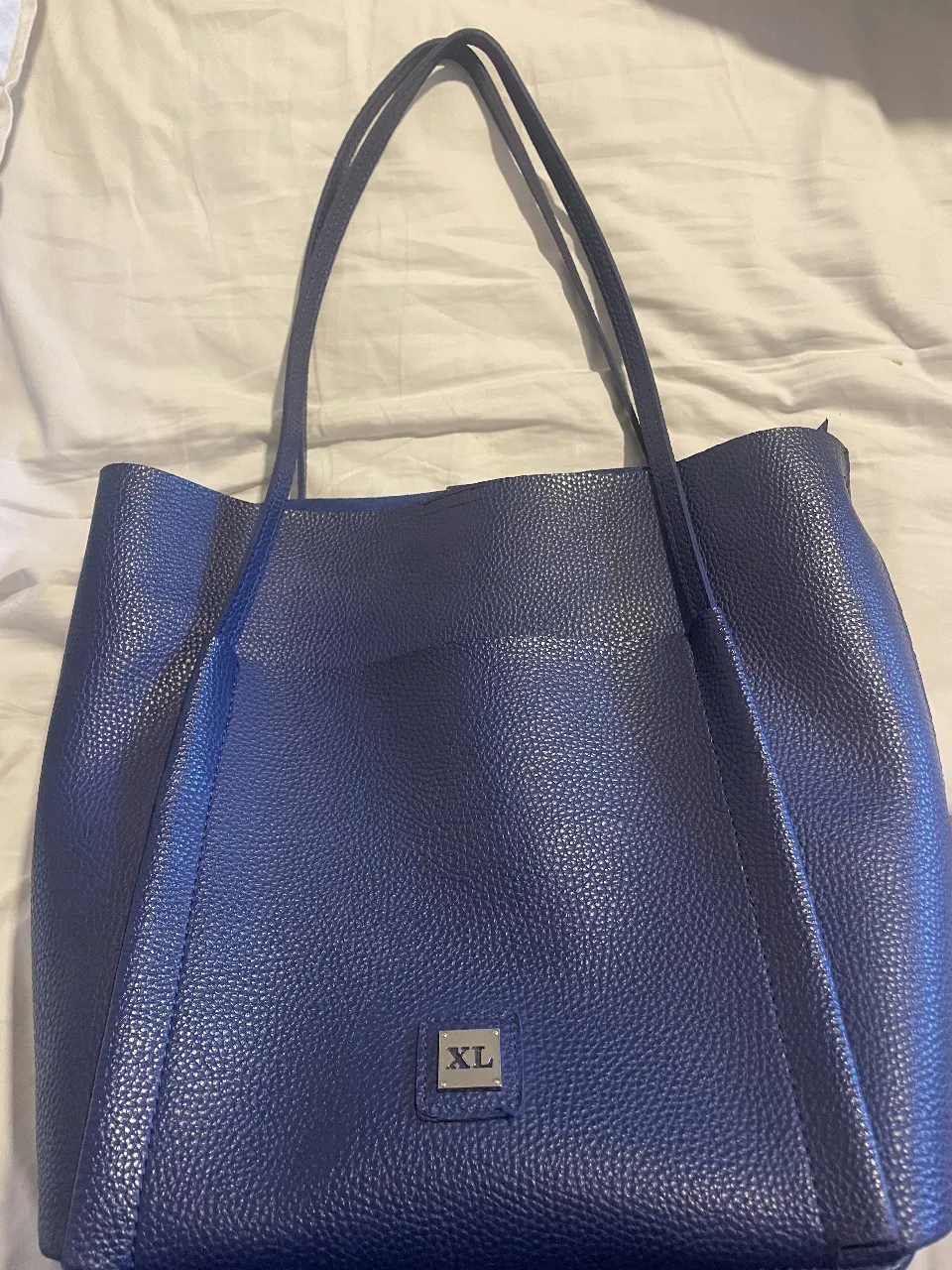 Bolso tote azul marino de cuero sintético, ideal para llevar todo lo necesario con estilo. Cuenta con un compartimento principal amplio y un bolsillo interno con cierre para mayor seguridad. Perfecto para el día a día o para llevar al trabajo.