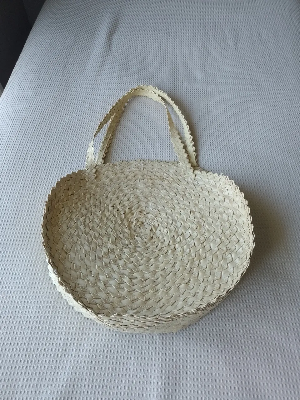 Bolso redondo de tejido artesanal con dos asas.