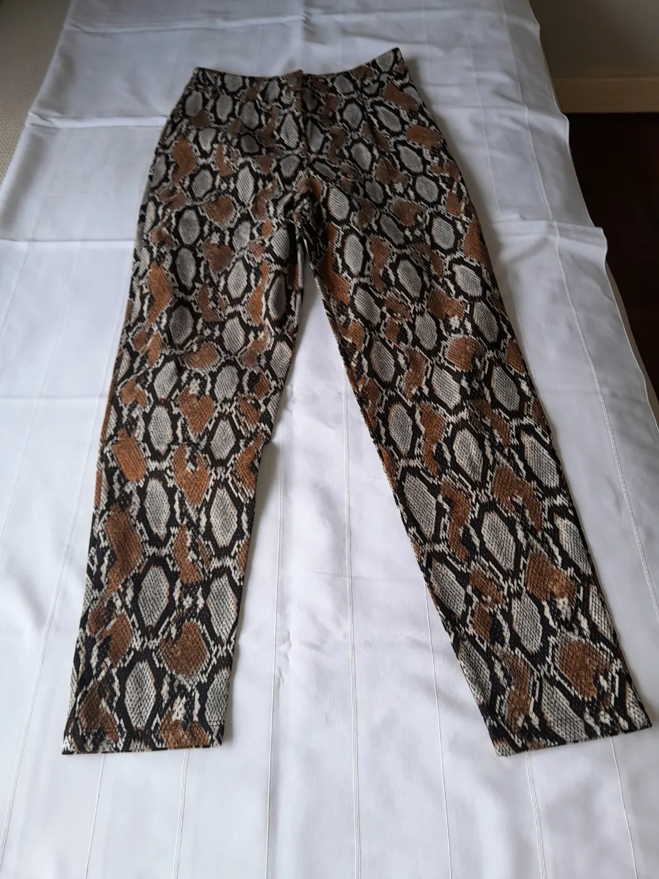 Pantalón estampado de serpiente, con cierre y botón.