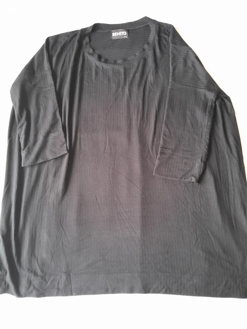 Remera negra de manga 3/4 con cuello redondo y textura acanalada.