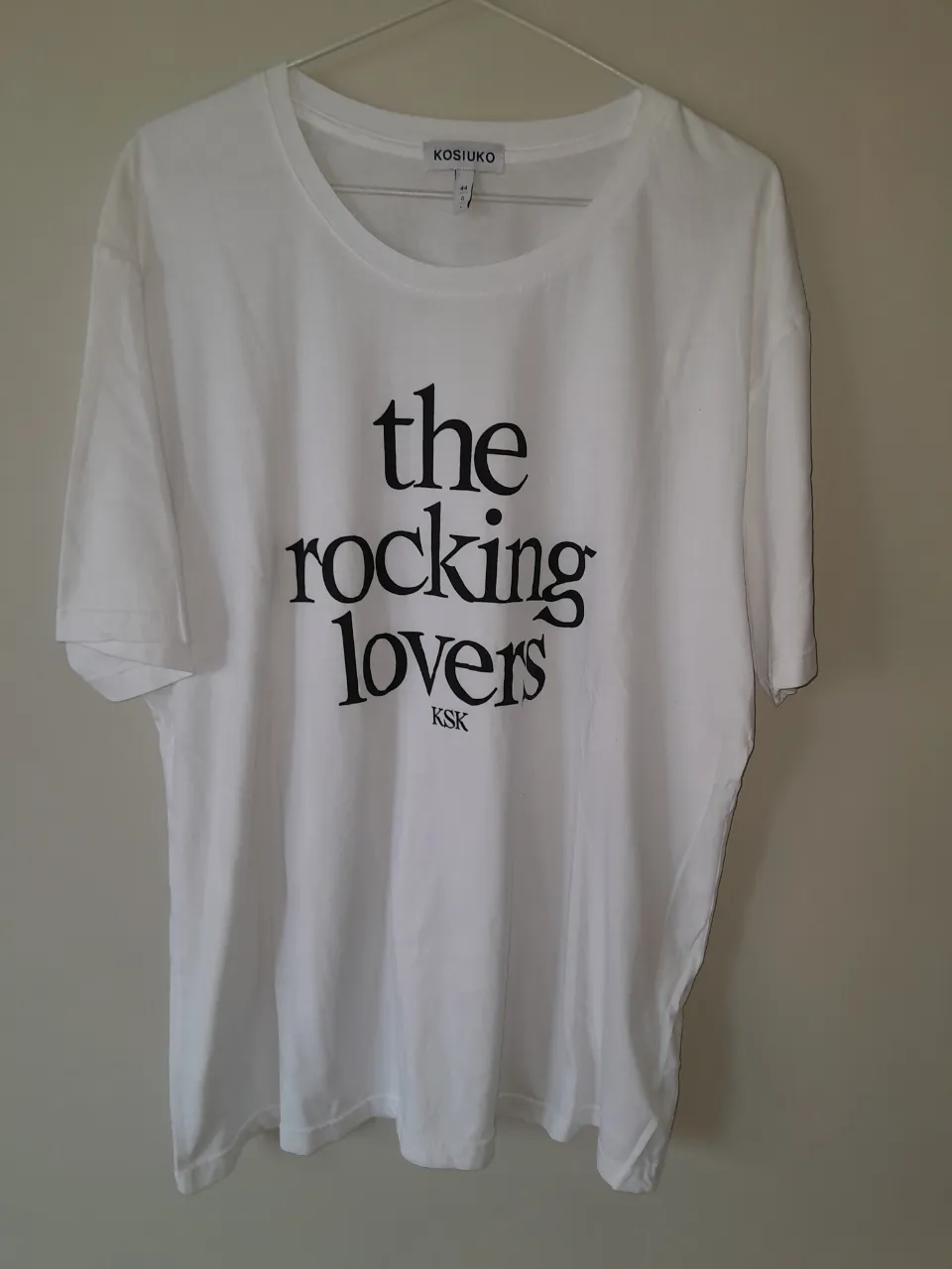Remera blanca de manga corta con estampa "the rocking lovers KSK" en negro.