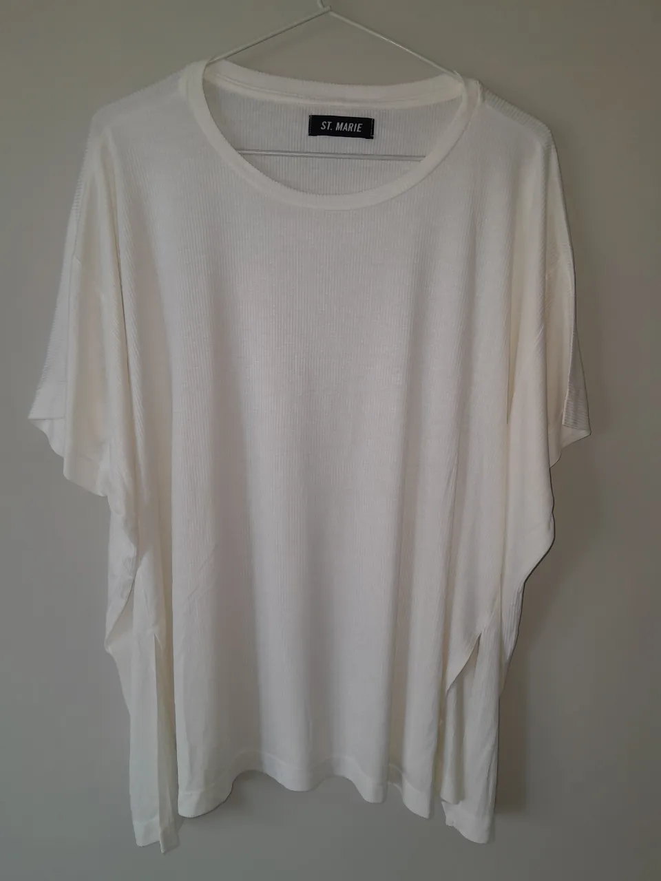 Remera blanca de manga corta con cuello redondo. Posee una textura acanalada vertical en toda la prenda.