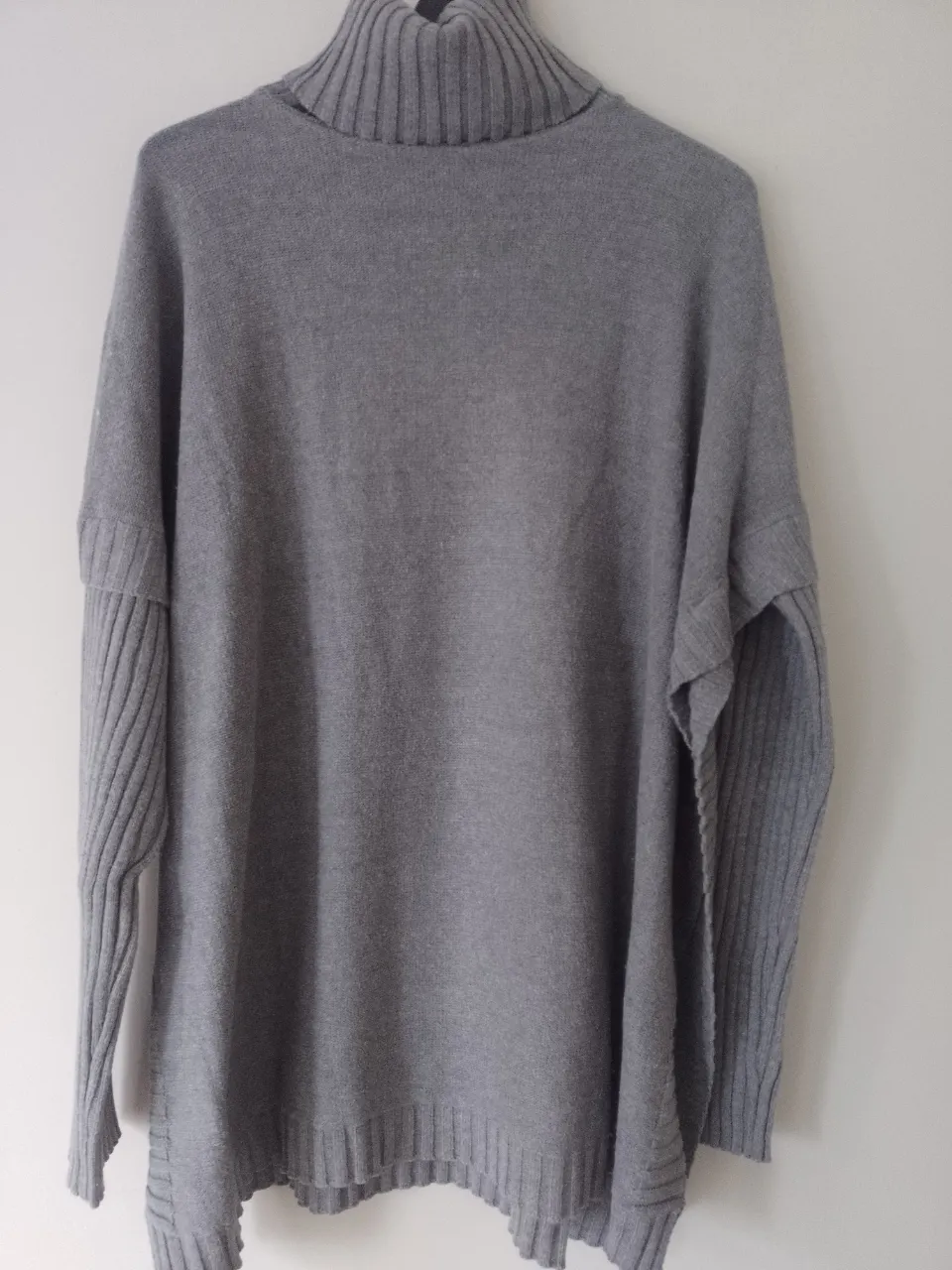 Sweater gris de cuello alto con mangas largas acanaladas.