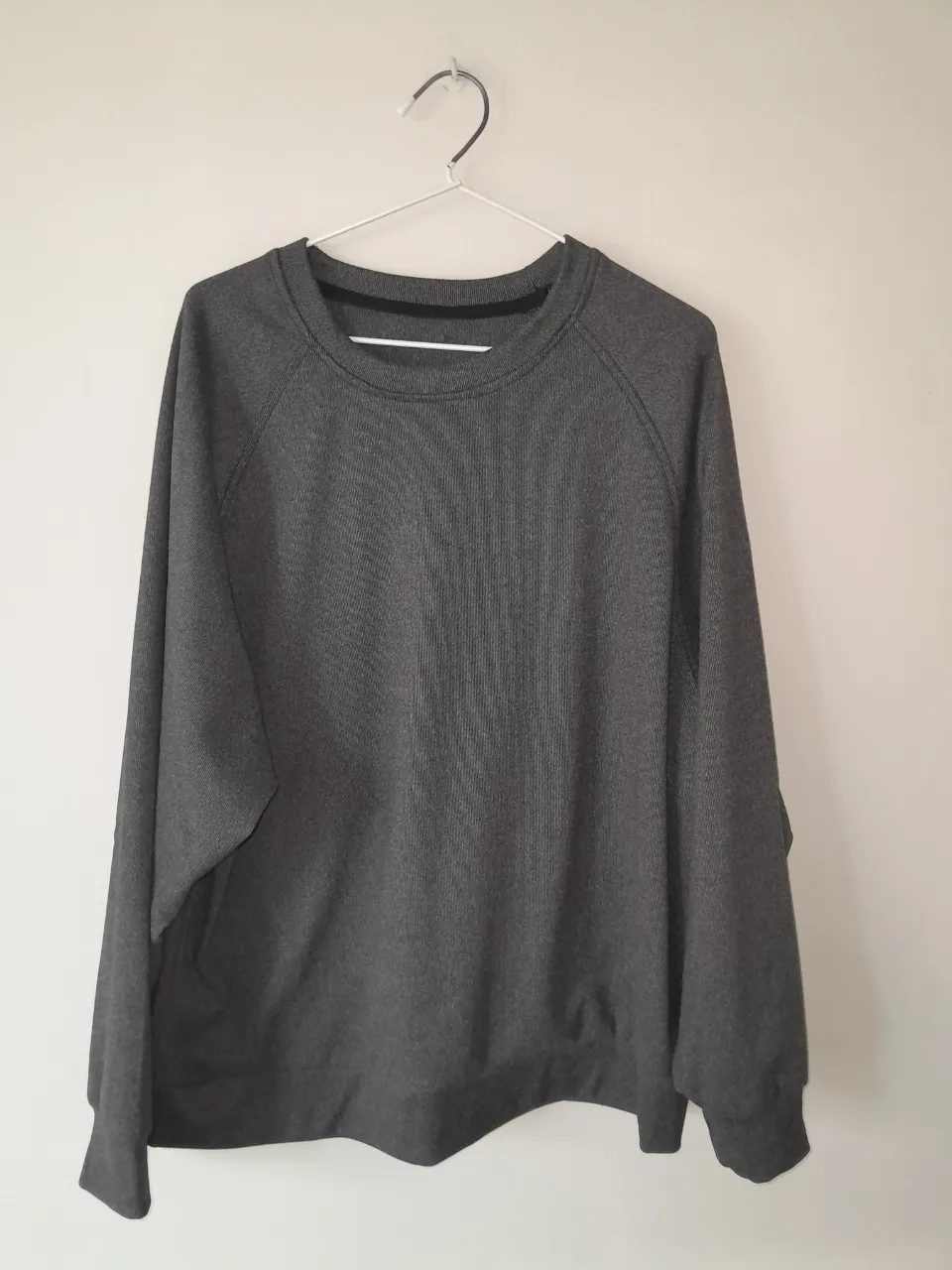 Buzo gris liso con cuello redondo y mangas ranglan.