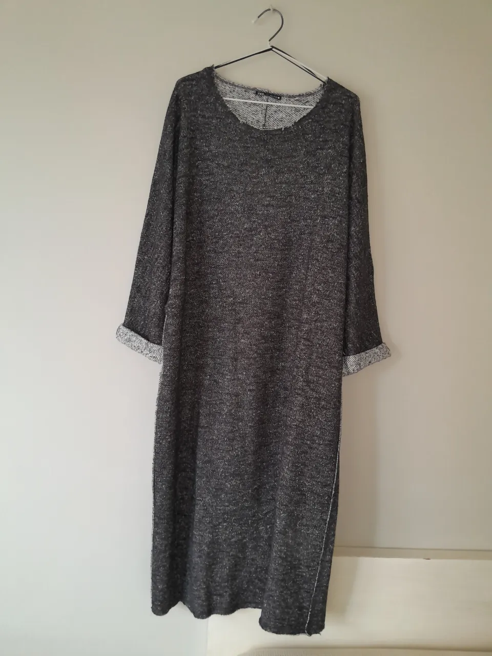 Vestido largo de manga larga, color gris jaspeado. Cuello redondo. Dobladillo en las mangas.