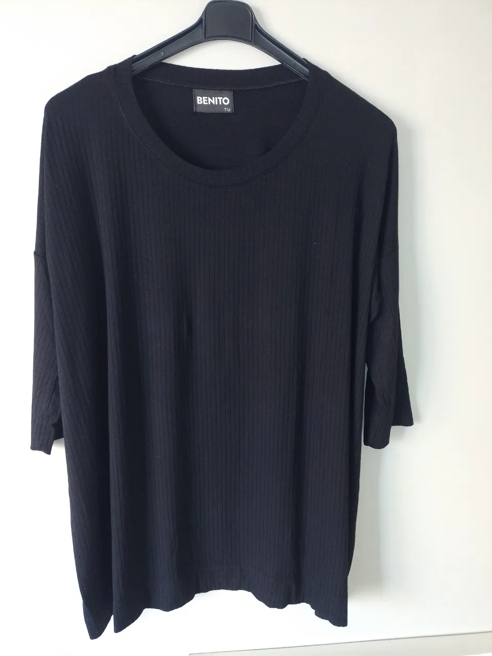 Remera negra de manga 3/4, con cuello redondo y textura acanalada. Diseño moderno y cómodo, ideal para el día a día.