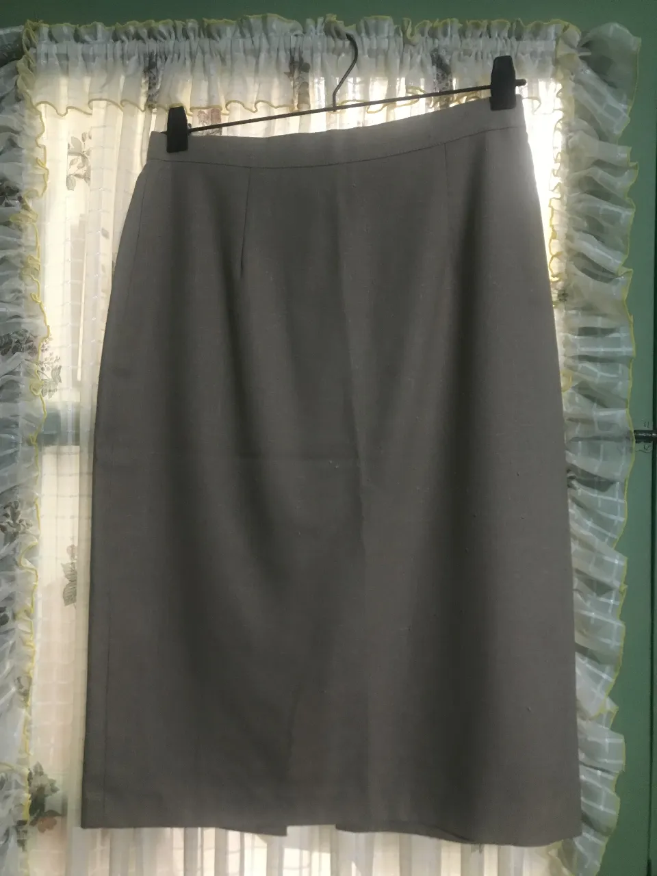 Pollera sastrera gris, de largo a la rodilla, con botones delanteros y corte recto. Ideal para un look formal o de trabajo.