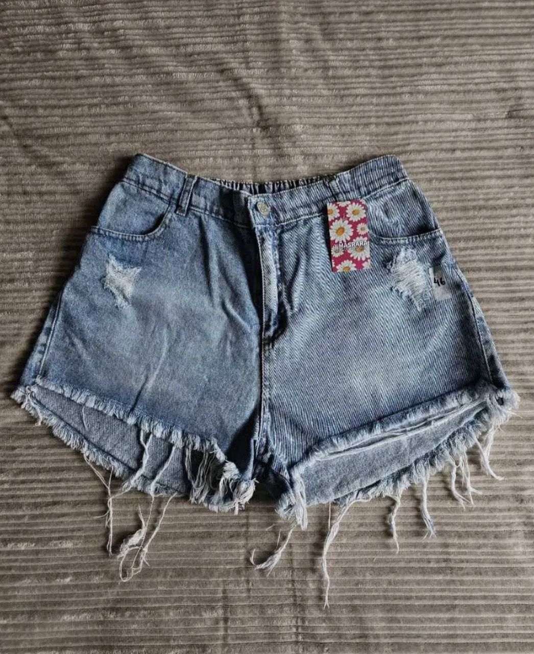 Shorts de jean liviani, tiro alto con roturas y detalles desflecados en los bordes. Cintura con elástico.