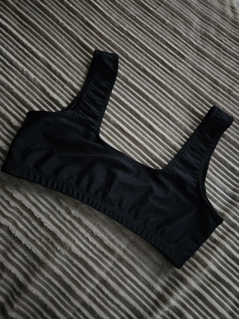 Top bikini negro, con tiras anchas y escote cuadrado. Posee textura acanalada.