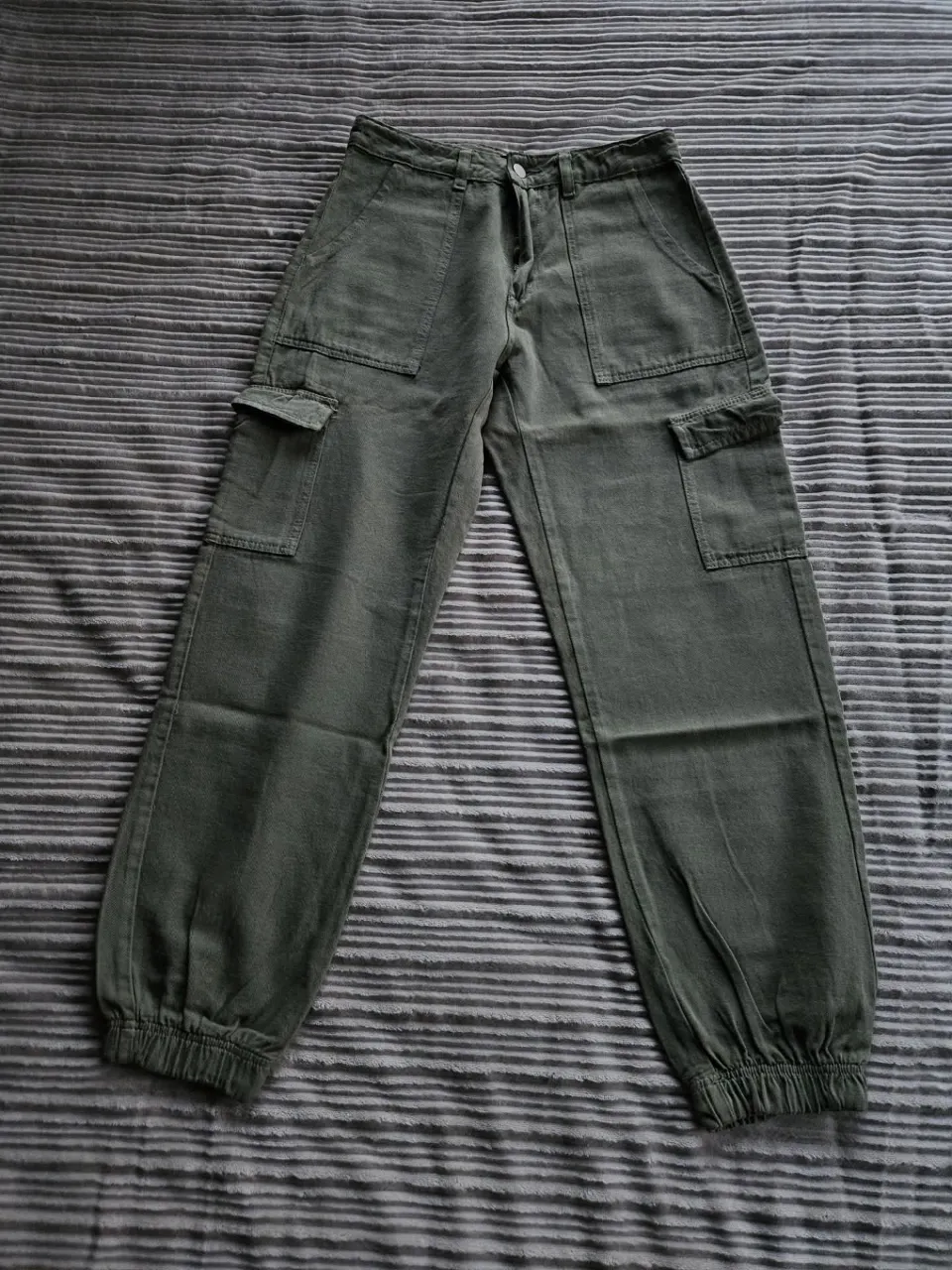 Pantalón cargo de color verde. Posee bolsillos en los laterales y en la parte trasera. Elástico en los tobillos.